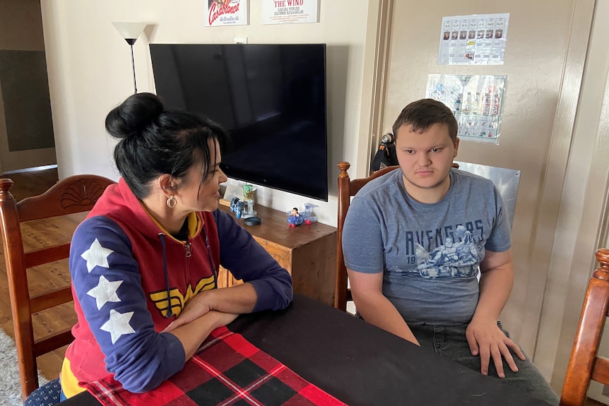 A woman and boy sitting at a table in a house