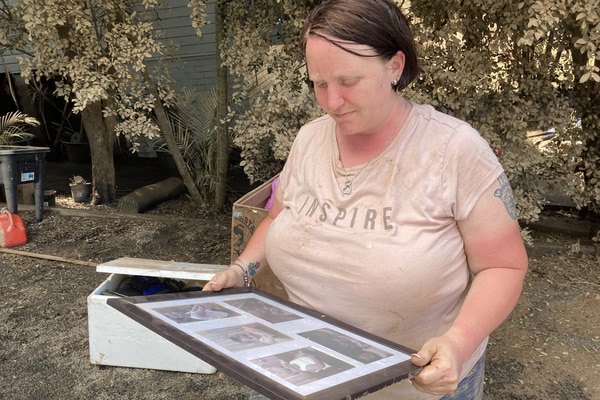 A woman hold a frames picture with lots of old photographs inside.