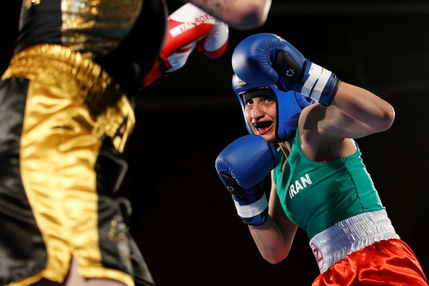 Sadaf Khadem stands in a defensive position with her left arm half-extended wearing a singlet, padded headgear and a mouthguard.