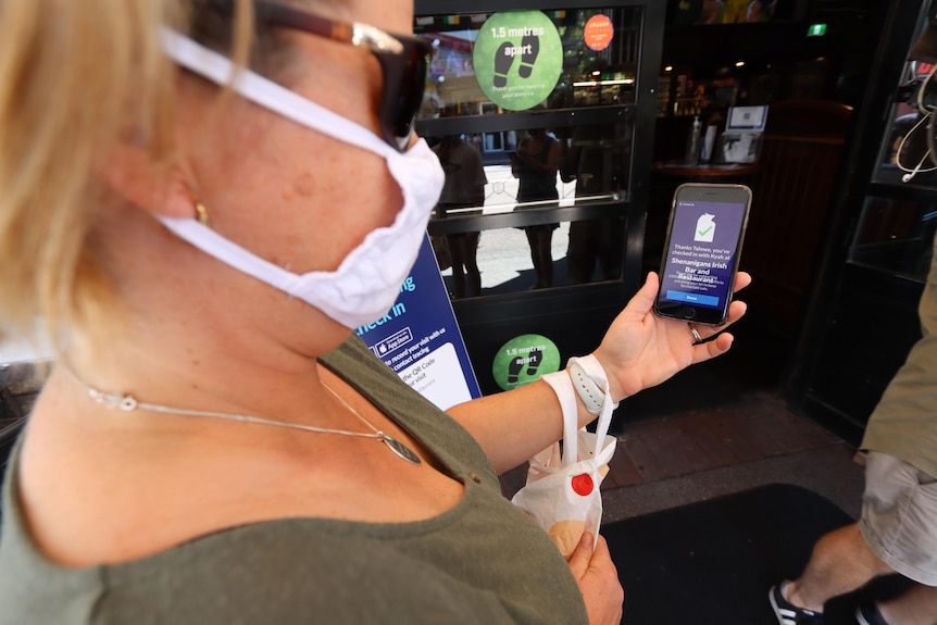 A woman uses the Territory Check In app to enter a venue.