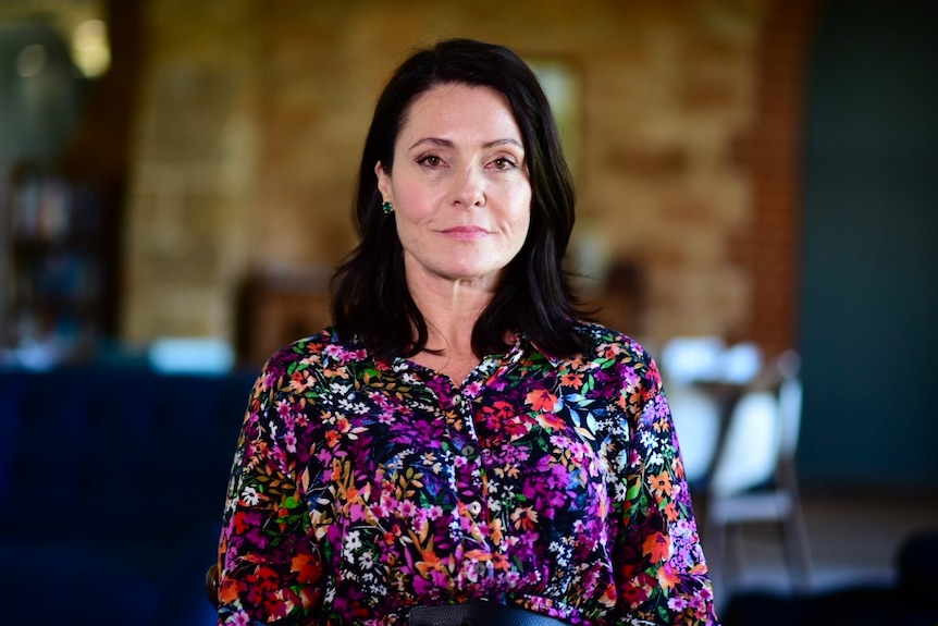 A woman with brown hair wearing a floral dress