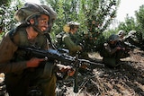 Israeli soldiers take up positions as they advance towards the Israel-Lebanon border.