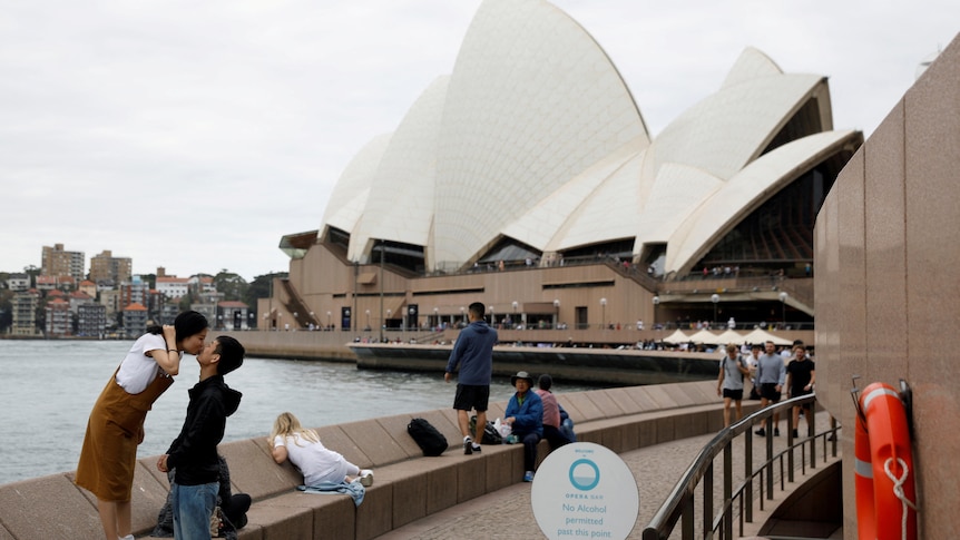 A chinese couple kissing in front of the Sydney Opera House