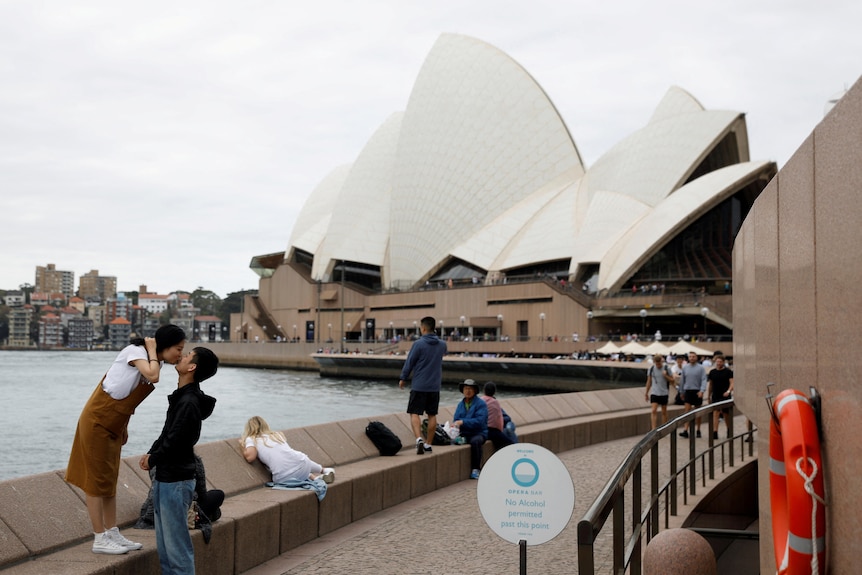 A chinese couple kissing in front of the Sydney Opera House