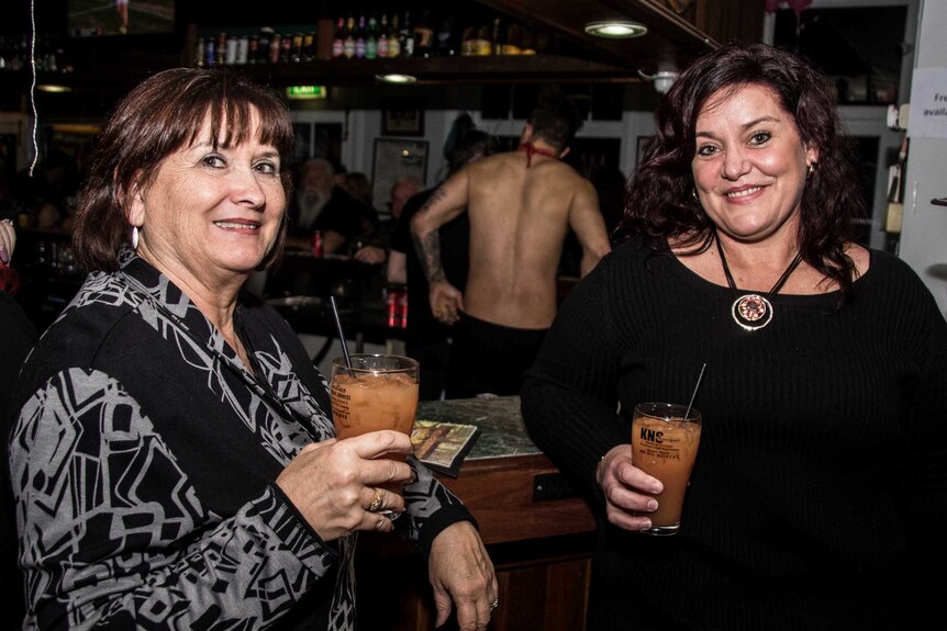 Patrons with male skimpy barmaid in background.
