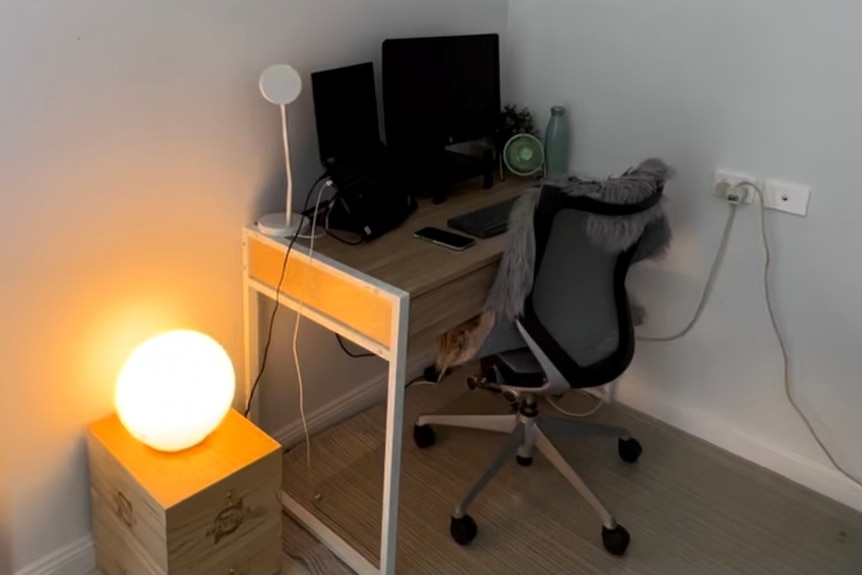 A computer sits on top of a desk in the corner of a room
