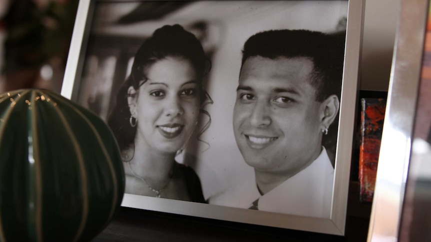A framed photograph of a young couple on their wedding day sits on a table.