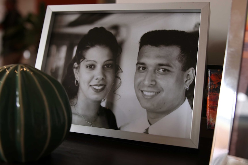 A framed photograph of a young couple on their wedding day sits on a table.
