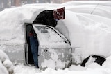A man opens the door of his snow-covered car in Pristina, Kosovo.