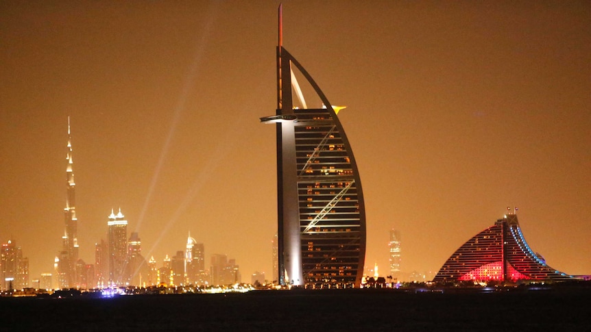 A general view shows Dubai's cityscape by night with the burj al arab in the foreground