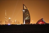 A general view shows Dubai's cityscape by night with the burj al arab in the foreground