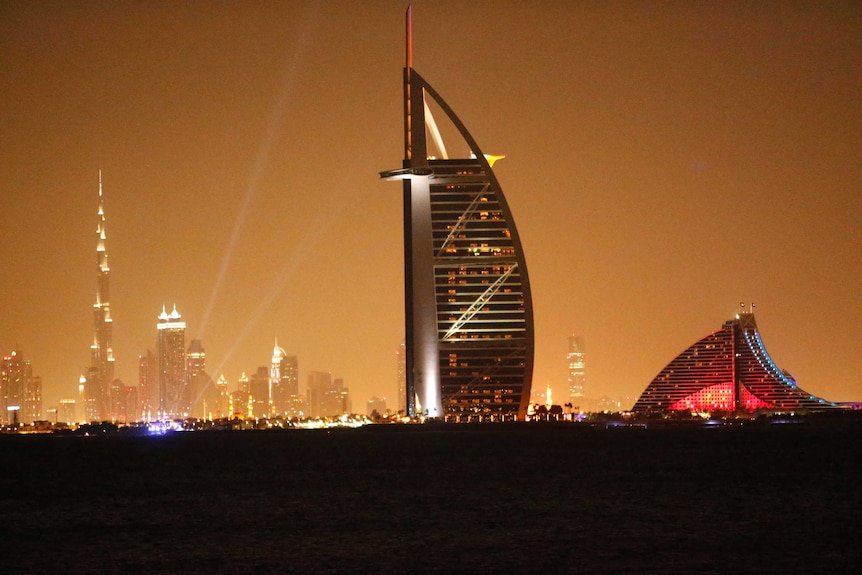 A general view shows Dubai's cityscape by night with the burj al arab in the foreground