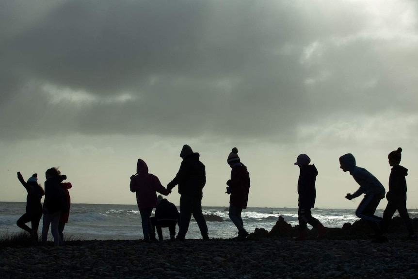 Kids silhouetted against the wild light off the coast