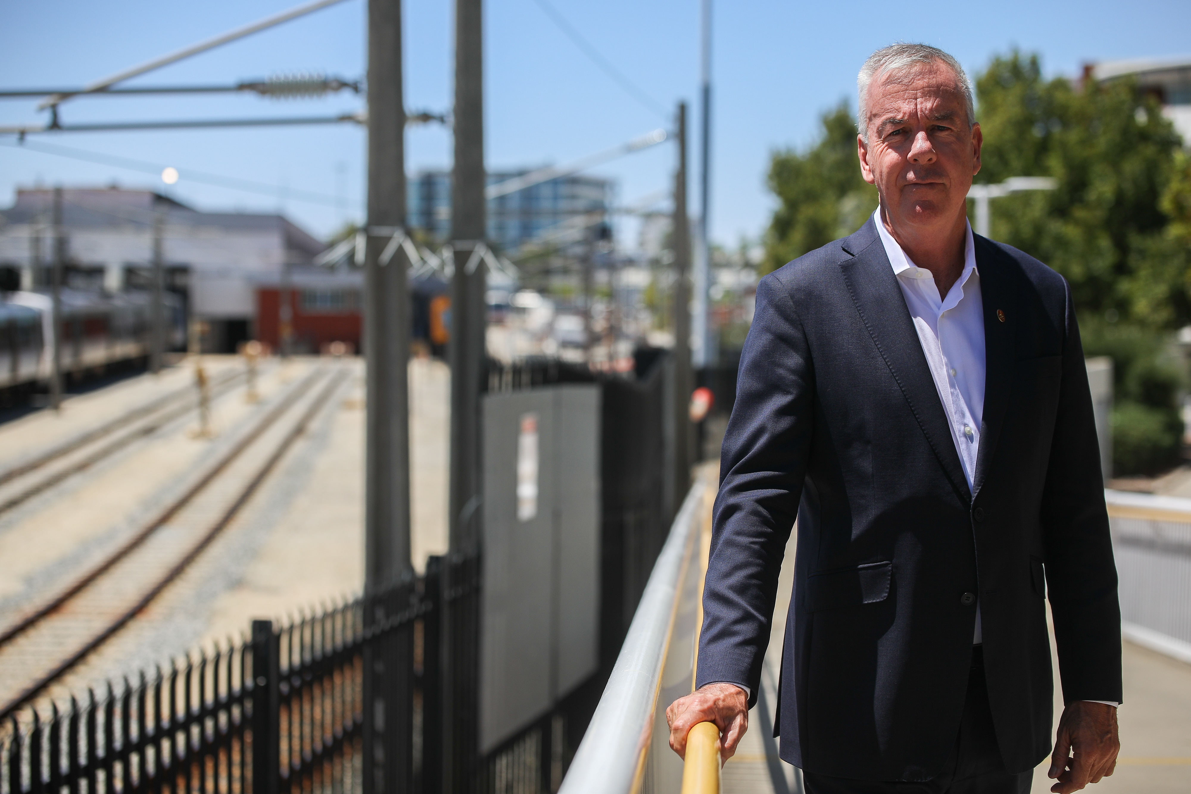 Стив Мартин стоит на пандусе рядом с железнодорожным депо.