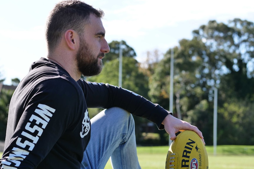 Footballer James Pedemont sits on his local footy oval, Sydney, June 2020.