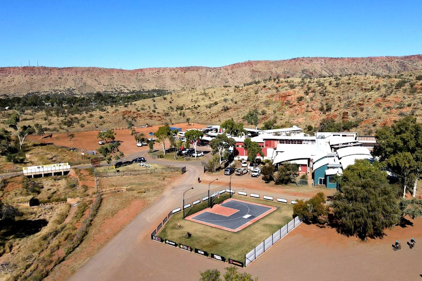 An aerial view of a school with a half-sized outdoor basketball court with just one hoop.