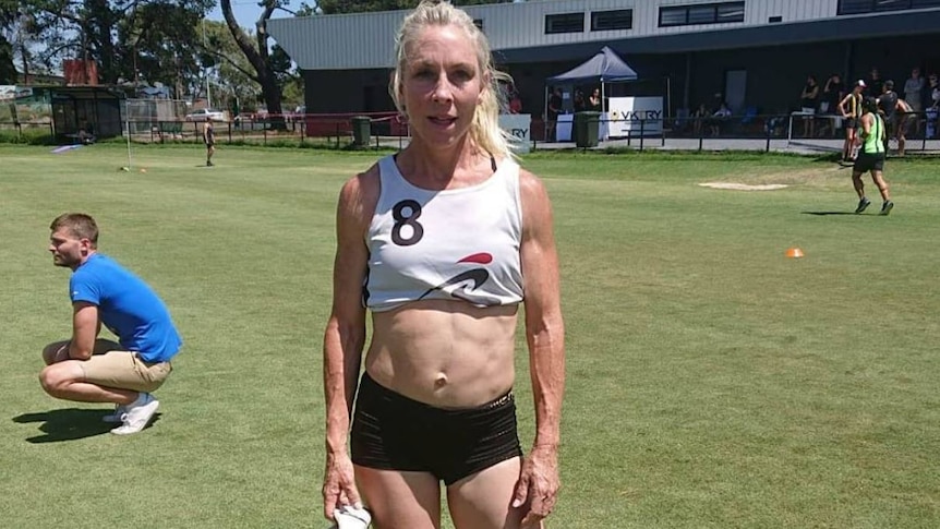 A woman in running gear looks straight at the camera.