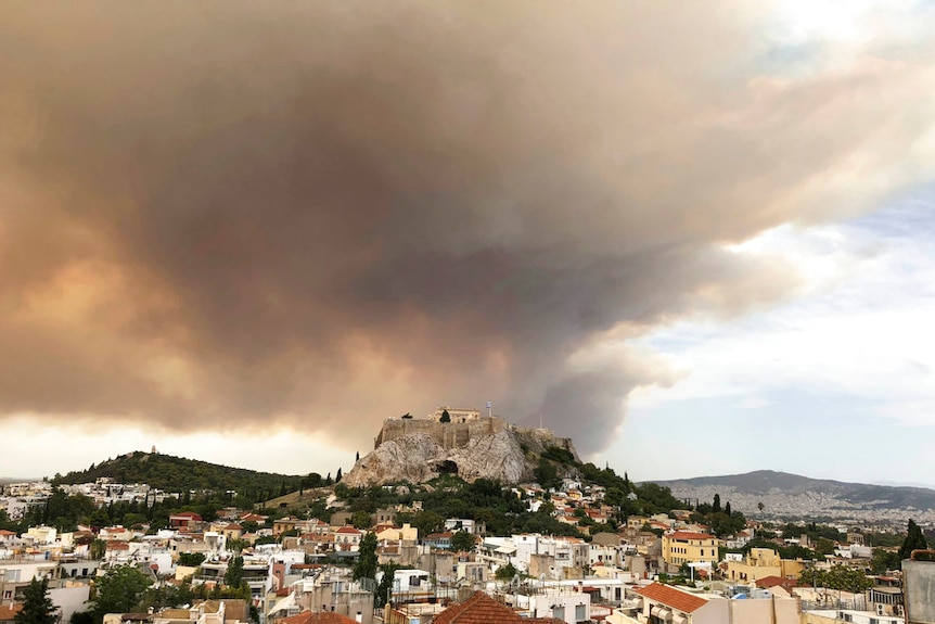 Big cloud of grey-brown smoke hangs in the sky over the Acropolis and surrounding area of Athens