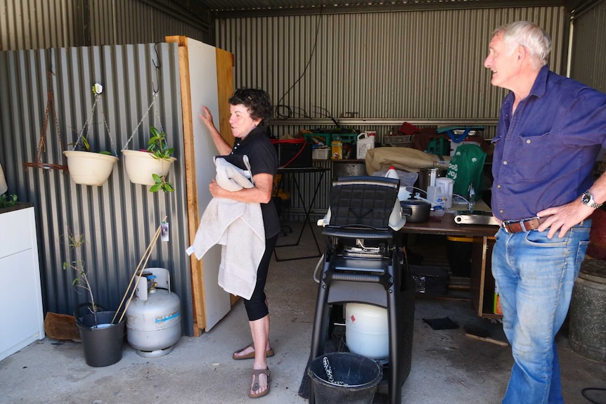 A middle-aged couple look at the inside of a makeshift home in a shed