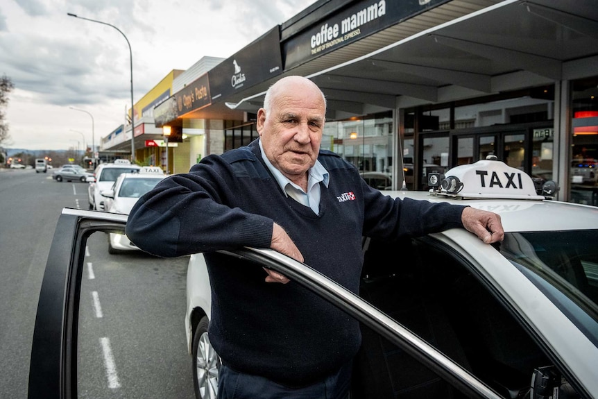 A man stands next to a car.