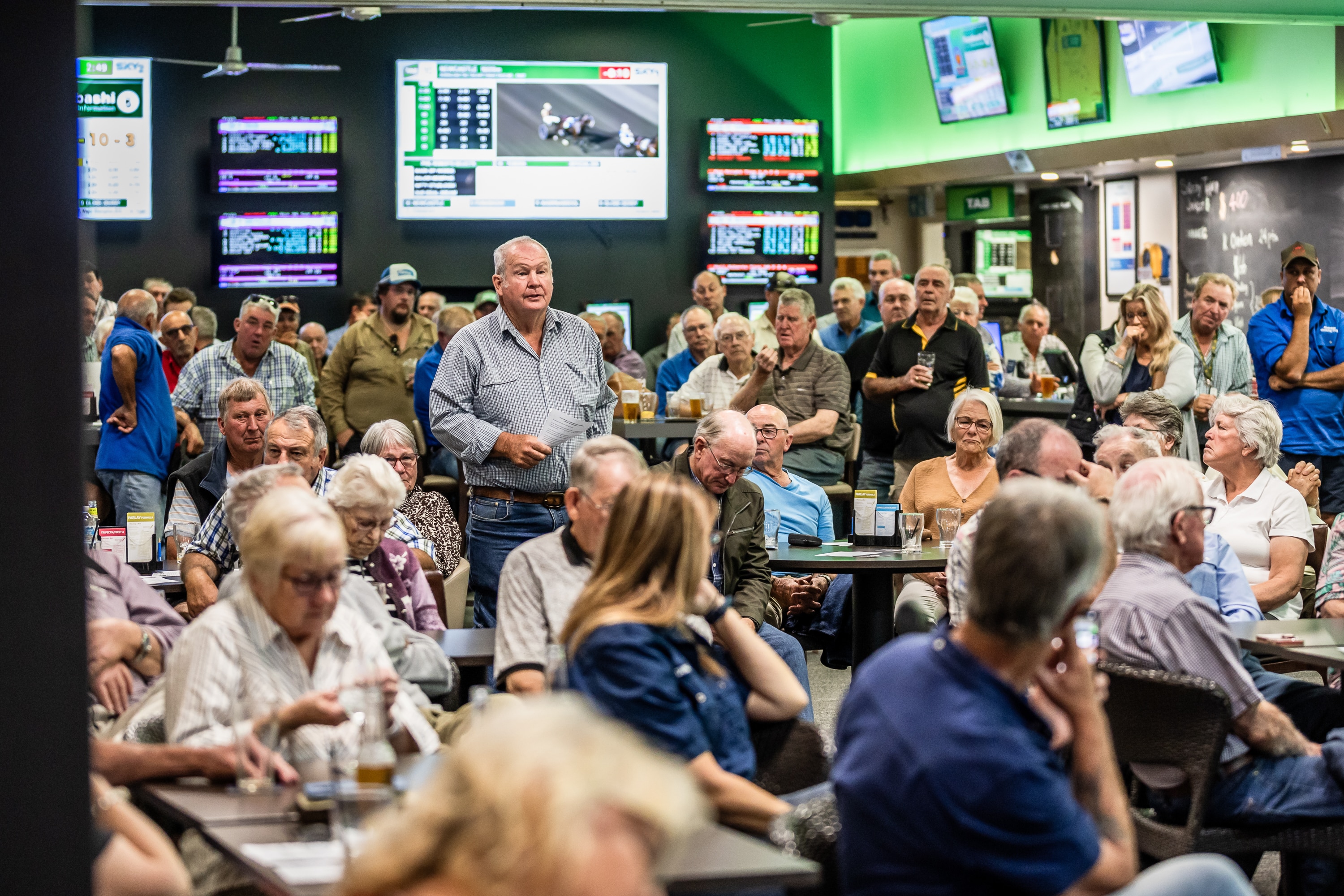 A man stands in a crowded room to ask a question.