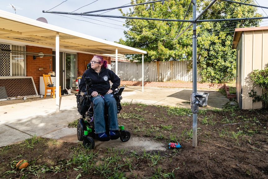 A woman in a wheelchair under a backyard clothes line