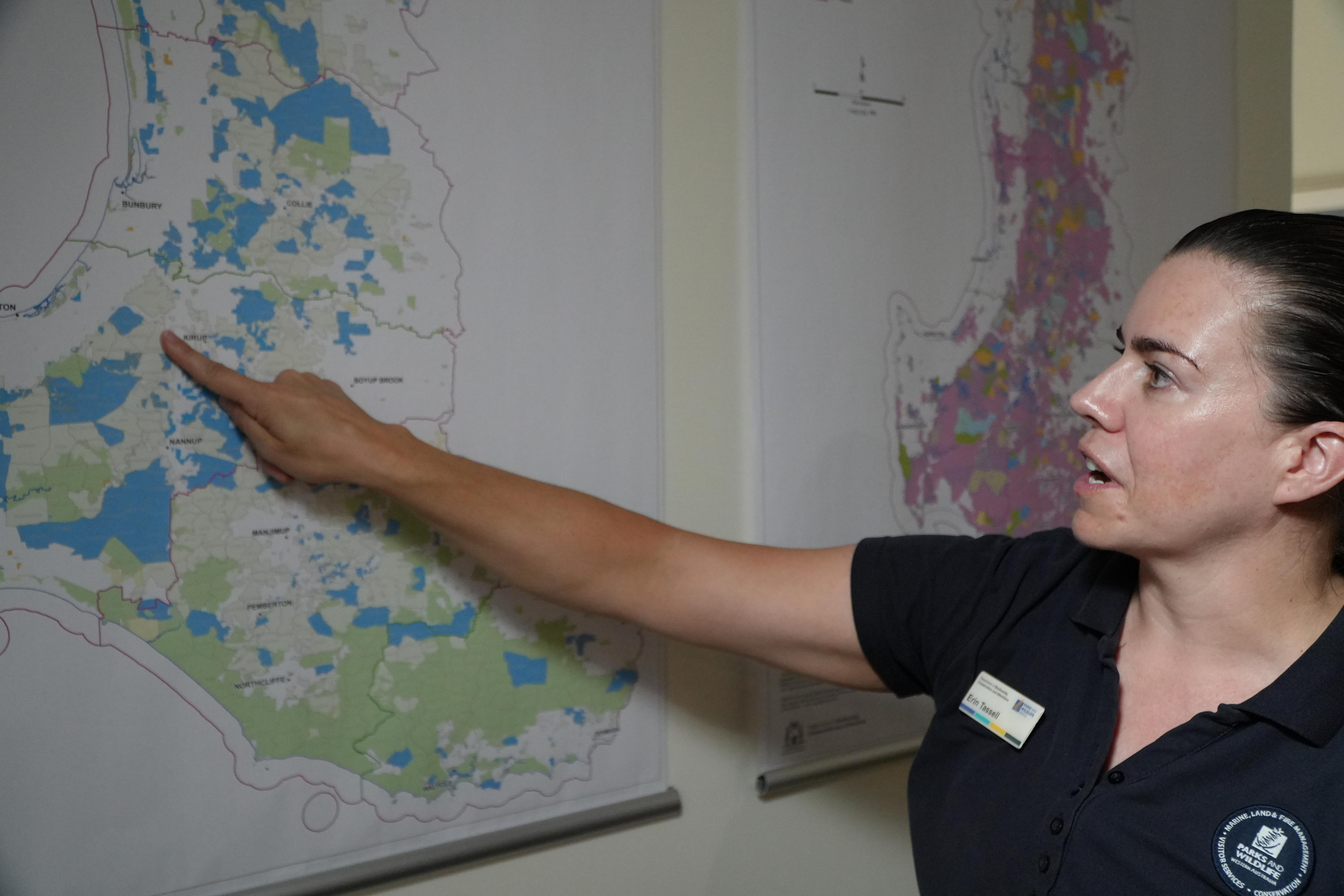 Erin Tassell aponta para um mapa.