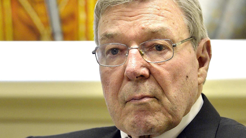 Upper body photo of Cardinal George Pell, sitting and listening.