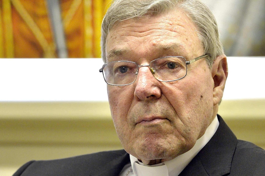 Upper body photo of Cardinal George Pell, sitting and listening.