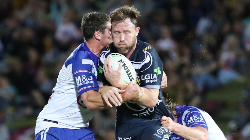 Gavin Cooper carries the ball and is tackled by two Canterbury Bulldogs players