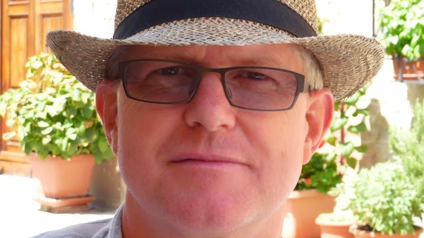 A close up of Ian Squire, wearing a hat and glasses.