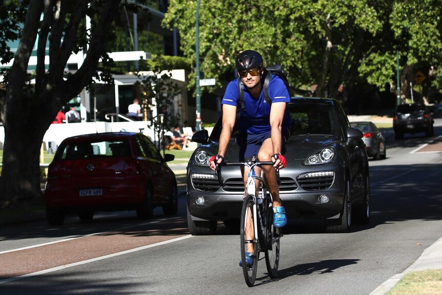 A wide shot of a cyclist rides along Kintail Road in the Perth suburb of Applecross