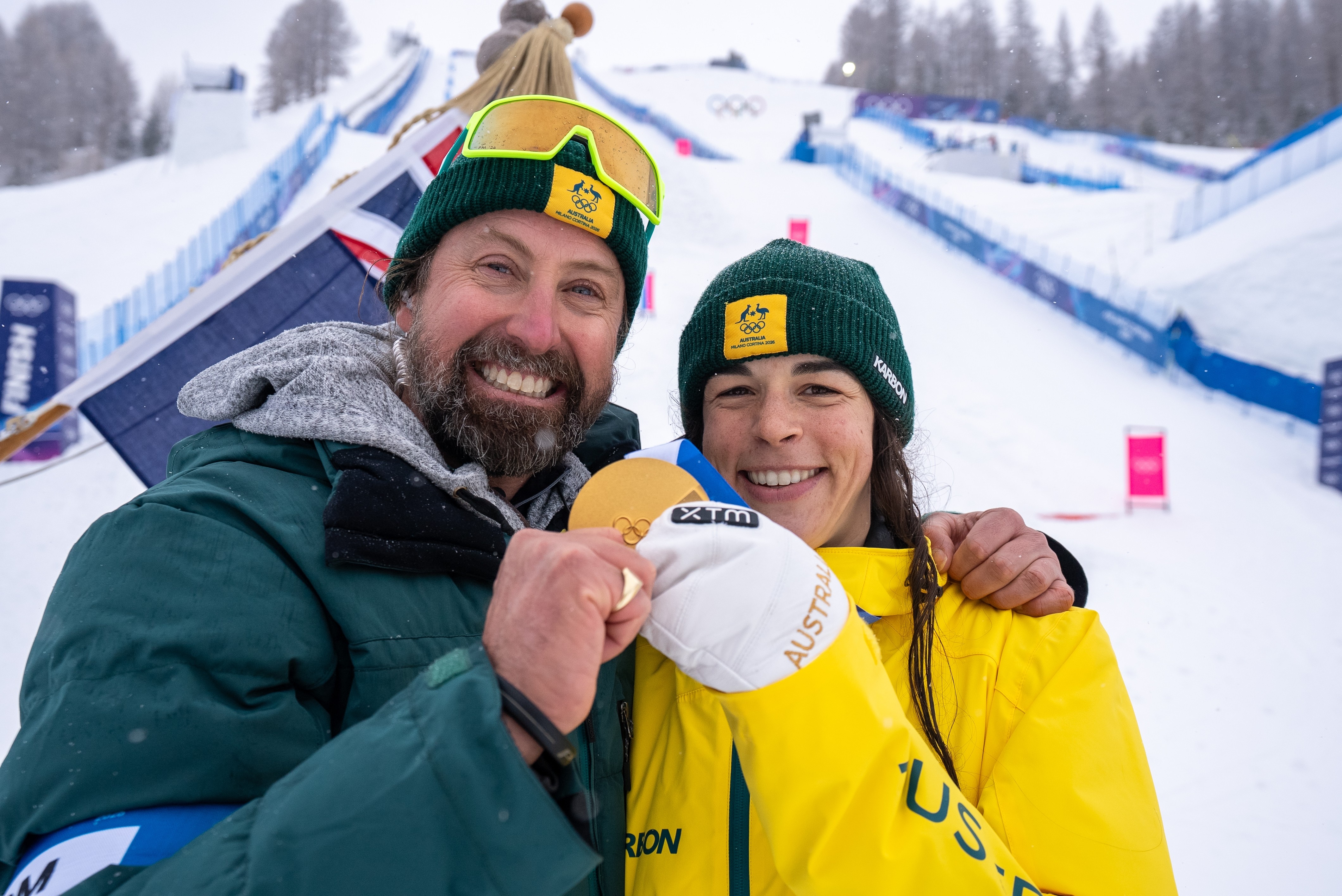 Jakara Anthony and Pete McNiel smile with an Olympic medal