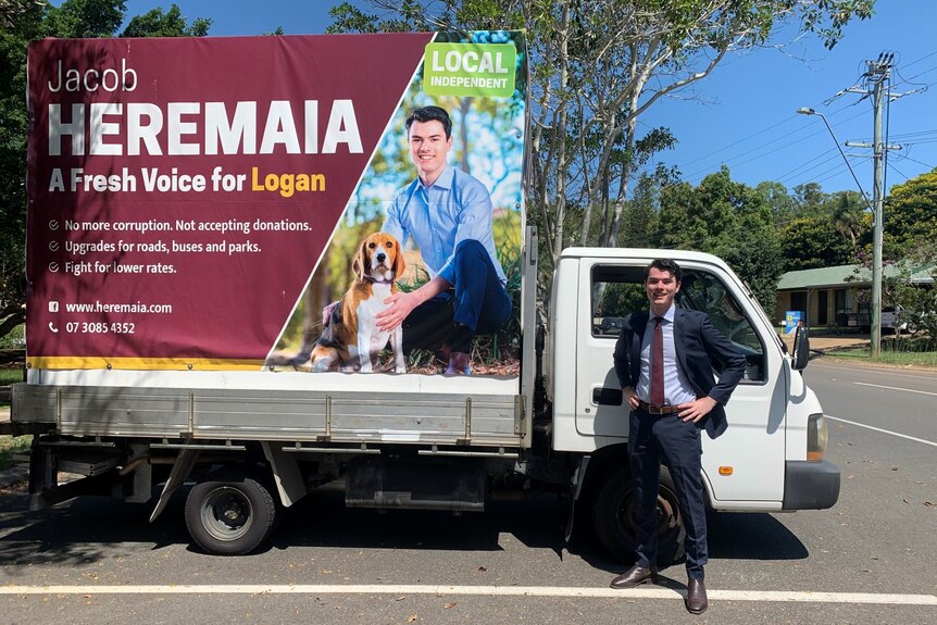Jacob Heremaia stands next to his large election sign