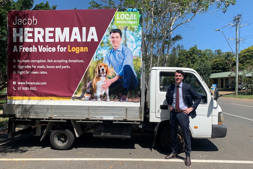 Jacob Heremaia stands next to his large election sign