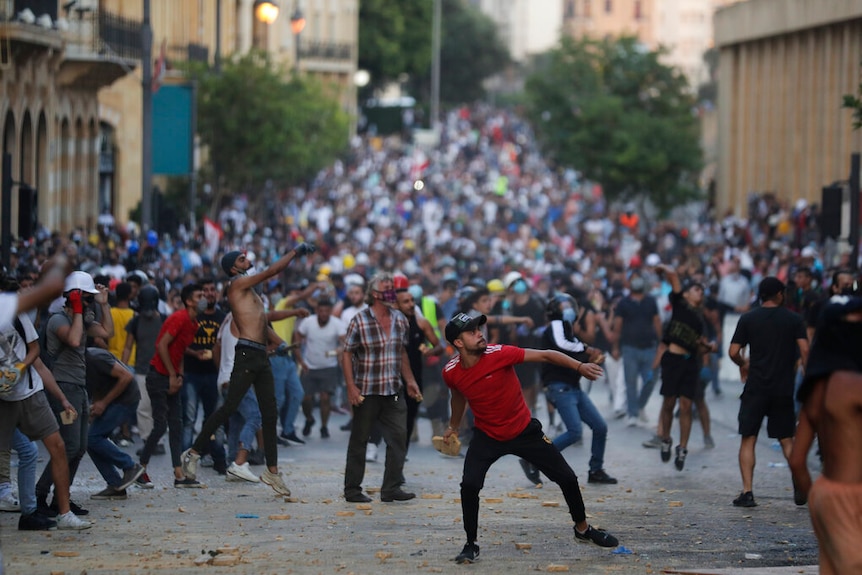 People throw stones during anti-government protest following Tuesday's massive explosion which devastated Beirut.