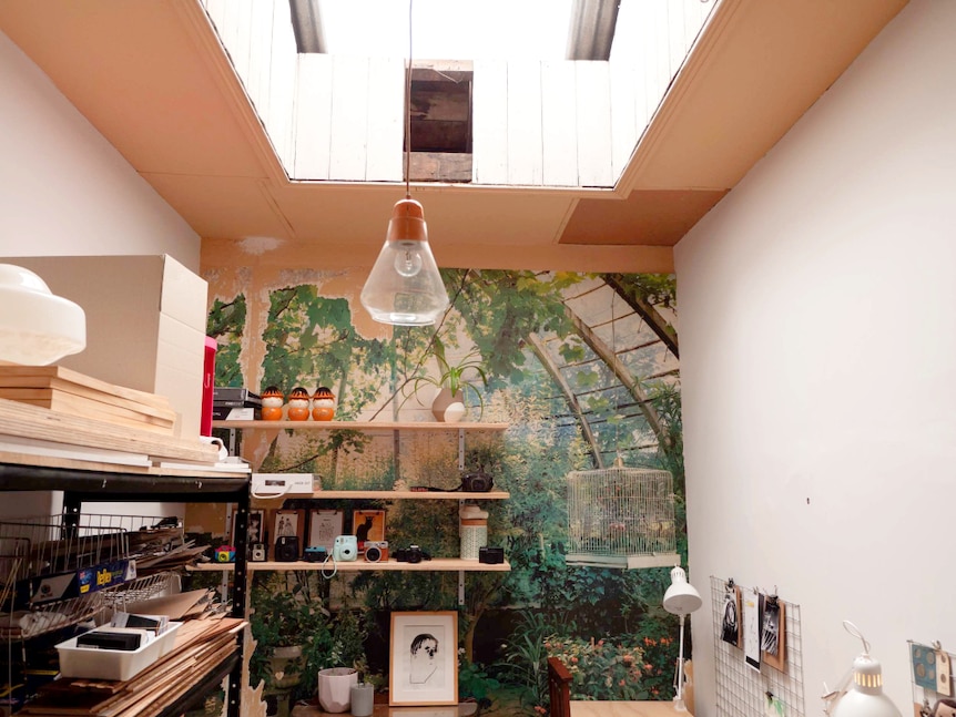 Office with skylight, desks and tattered photographic mural on far wall.