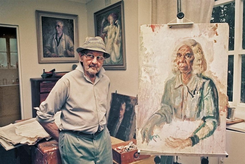 Australian artist Arthur Murch standing next to a portrait of Rubina Namatjira on an easel