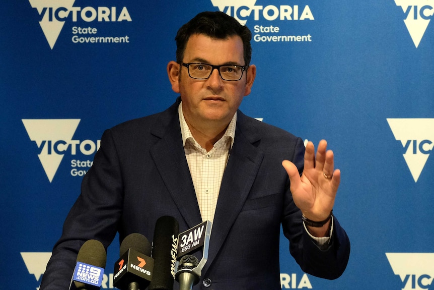 Daniel Andrews gestures with is left hand at a press conference.