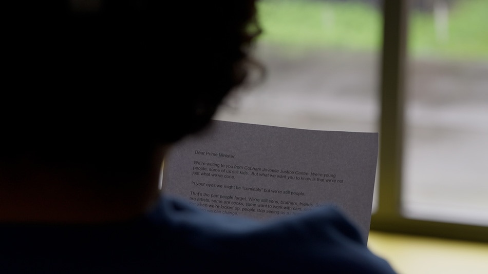 Un joven lee en voz alta una carta que él y sus compañeros de prisión escribieron al Primer Ministro desde prisión.