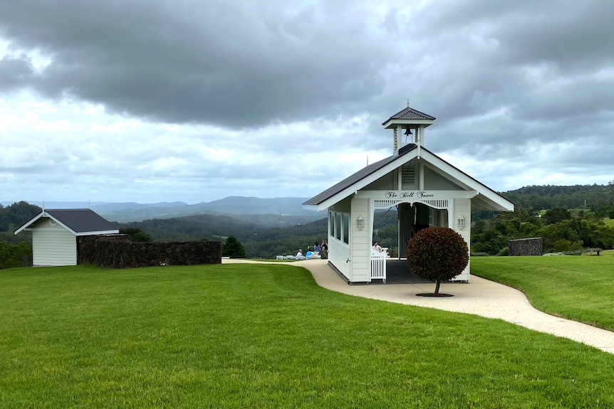 a small white chapel like building with hinterland views behind