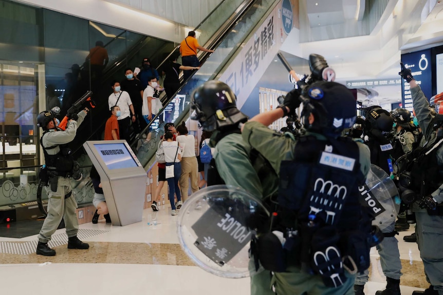 Riot police raise their pepper spray projectile inside a shopping centre as they disperse protesters.