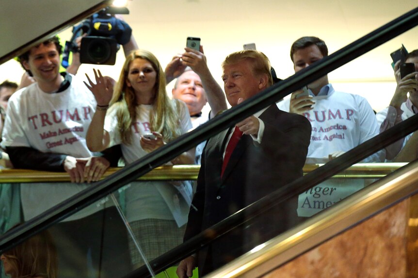 Donald Trump gives the thumbs up as he descends an escalator at Trump Tower