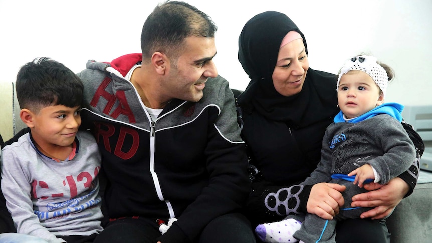 Syrian refugee Ammar Sawan, his wife Sanaa with with one of their sons and smile at their 1-year-old daughter.