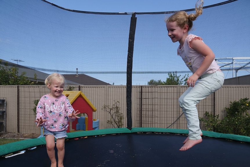 Two little girls laughing while bouncing on their new trampoline
