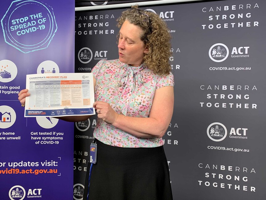 ACT Chief Health Officer Kerryn Coleman holding a chart showing Canberra's coronavirus recovery plan.