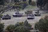 Four army tanks lined up in the grass.
