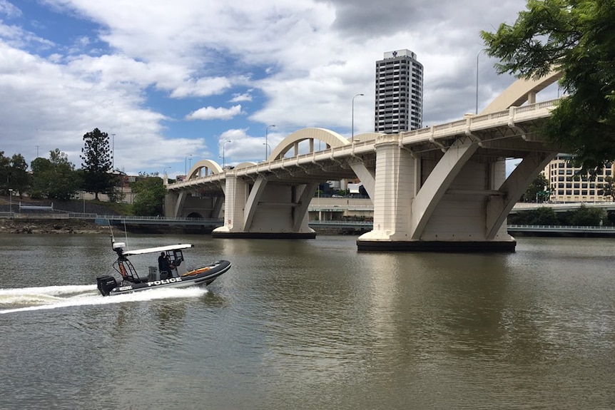 Water police pass the William Jolly Bridge in Brisbane.