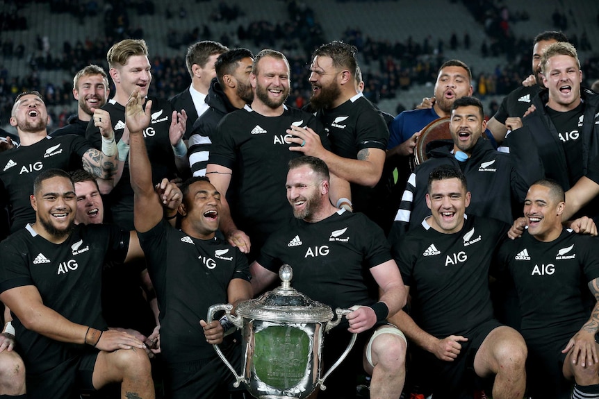 The All Blacks pose for a photo around the Bledisloe Cup after defeating Australia's Wallabies in Auckland.