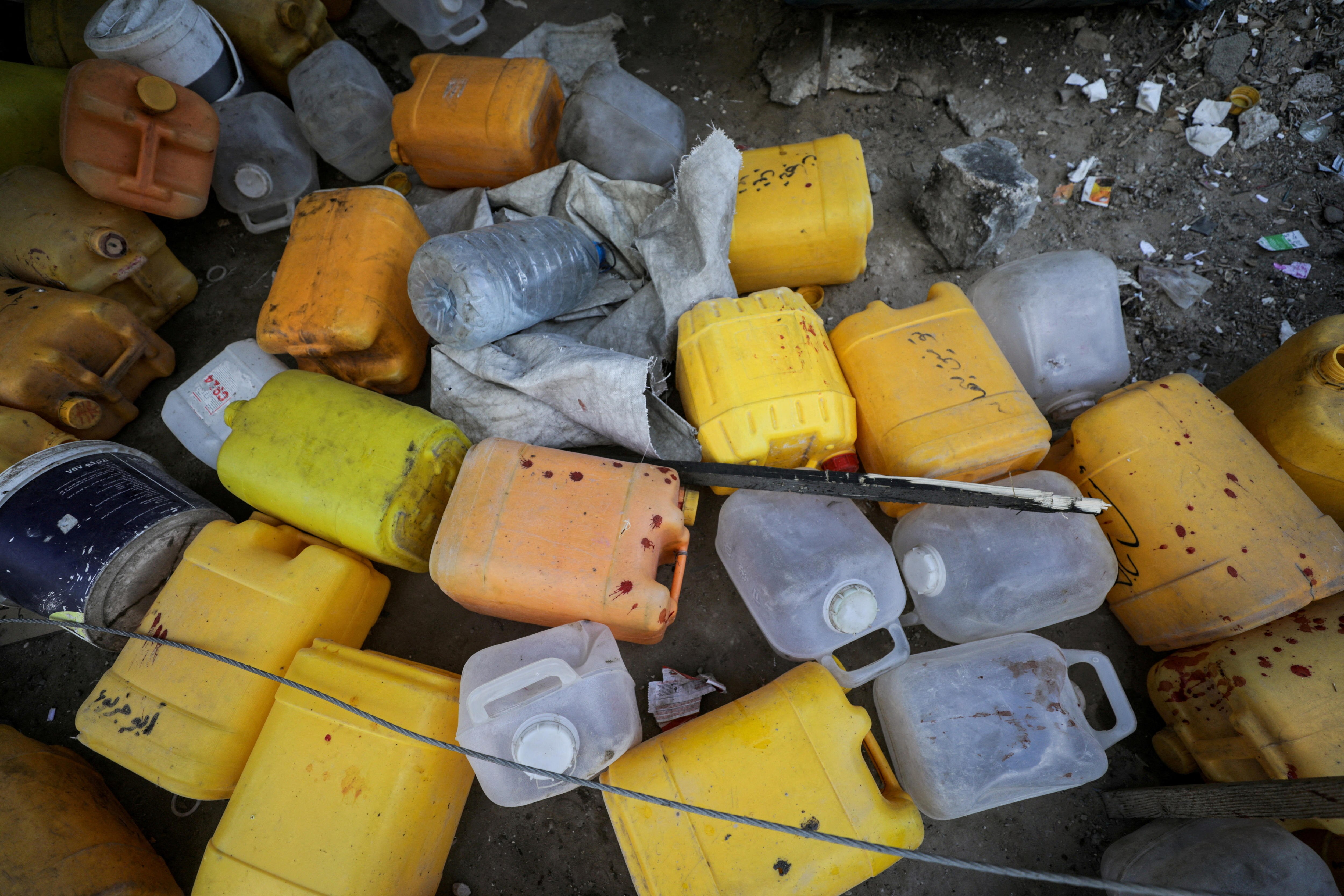 A dozen jerry cans on the ground, with blood splatter on them.